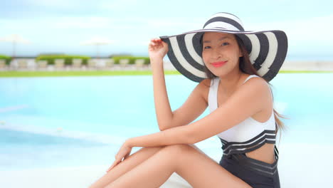 A-young-Asian-woman-enjoying-her-holiday,-next-to-the-hotel-swimming-pool