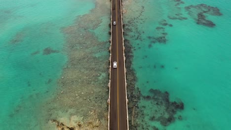 Aerial-view-of-car-bridge-over-turquoise-water-on-tropical-island