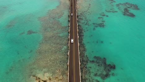 aerial view of car bridge over turquoise water on tropical island