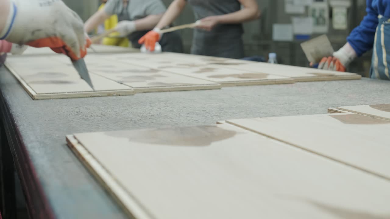 Workers Applying Filler to Wooden Boards in a Factory