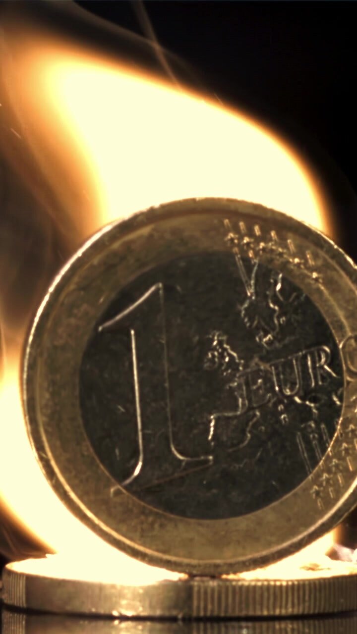 Una moneta da un euro che brucia, a simboleggiare la crisi economica