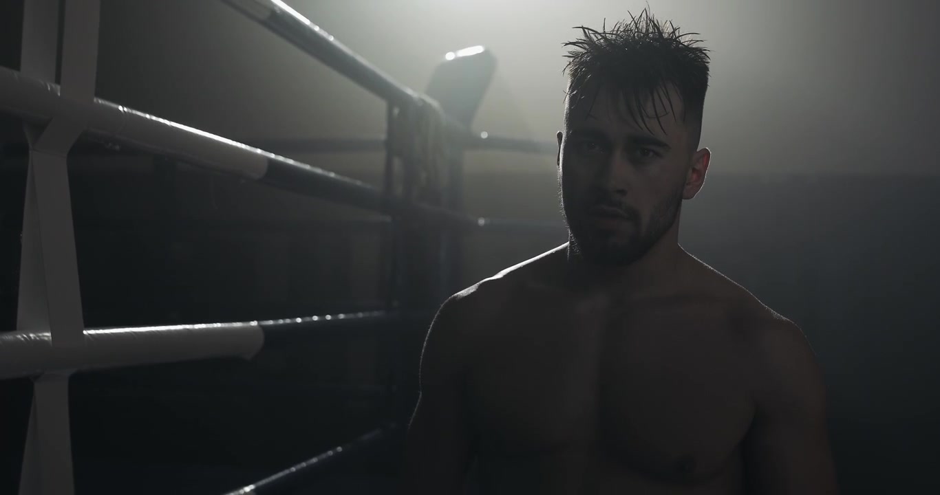 Pugile uomo determinato in piedi in un ring di pugilato buio