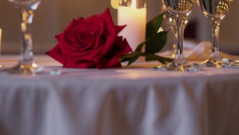 elegante mesa que muestra un ambiente romántico con una rosa roja, velas iluminadas y copas de champán, perfecto para una ocasión especial