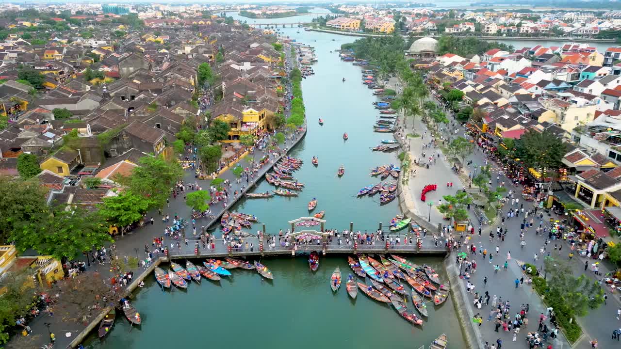 Aerial view of Hoi An bridge over river with tourist traffic and boats passing through heart of city, scenic beauty of Vietnam.