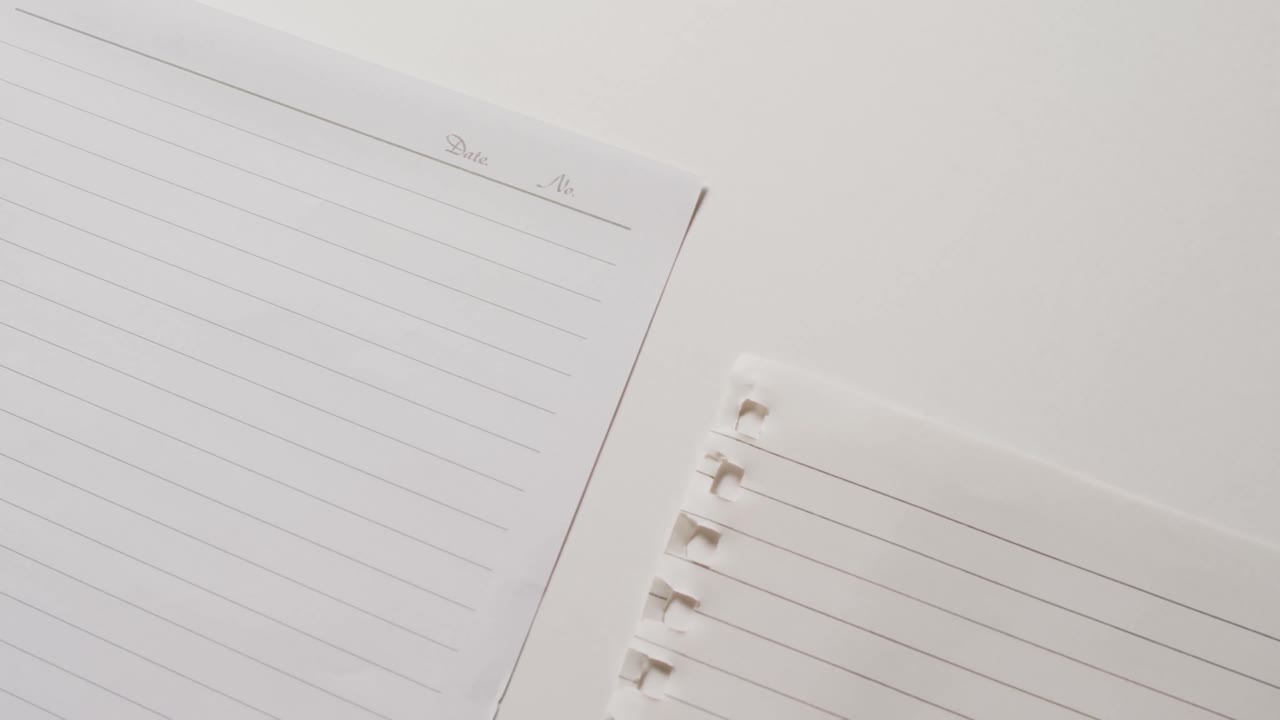 Video of close up of four sheets of notebook paper on white background