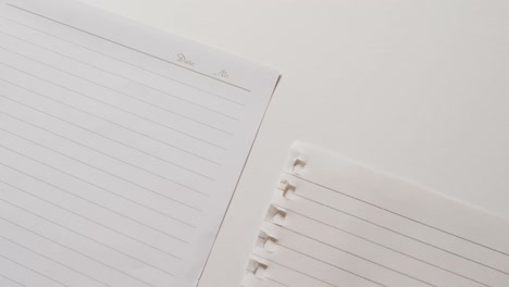 Video-of-close-up-of-four-sheets-of-notebook-paper-on-white-background