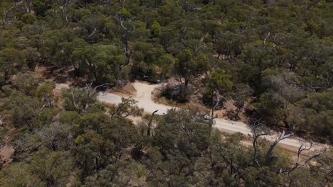 Auto-Fährt-Auf-Einer-Schotterstraße-Durch-Den-Nationalpark,-Während-Die-Drohne-Filmisch-Herumschwenkt