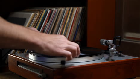 person selecting and placing a vinyl record on a turntable