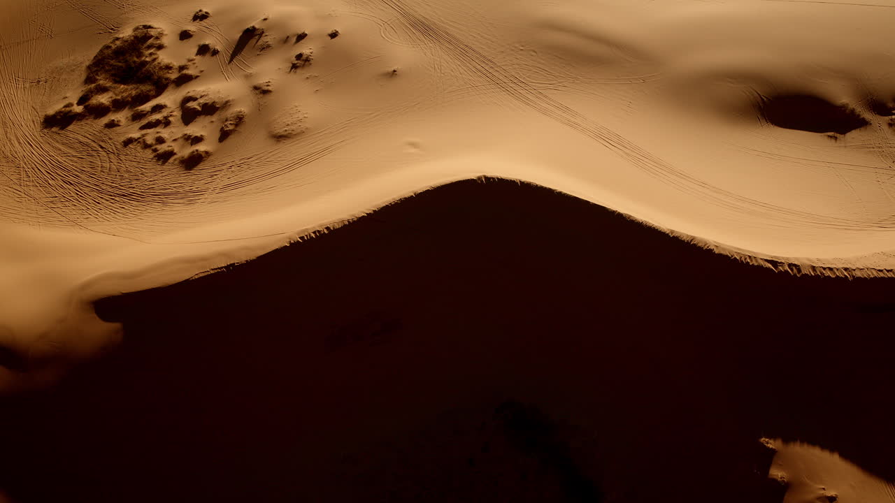 An overhead drone shot shows a canvas of pink sand and abstract shapes in Utah’s southern desert.