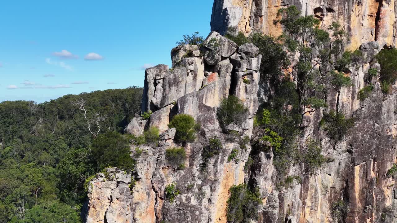 Aerial view of Nimbin Rocks, showcasing towering cliffs and lush forest under bright sunlight