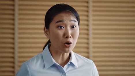 a woman in a light blue shirt speaks with intensity in a modern office. she shares her thoughts on a significant issue. the shelves behind her add to the academic ambiance of the space.