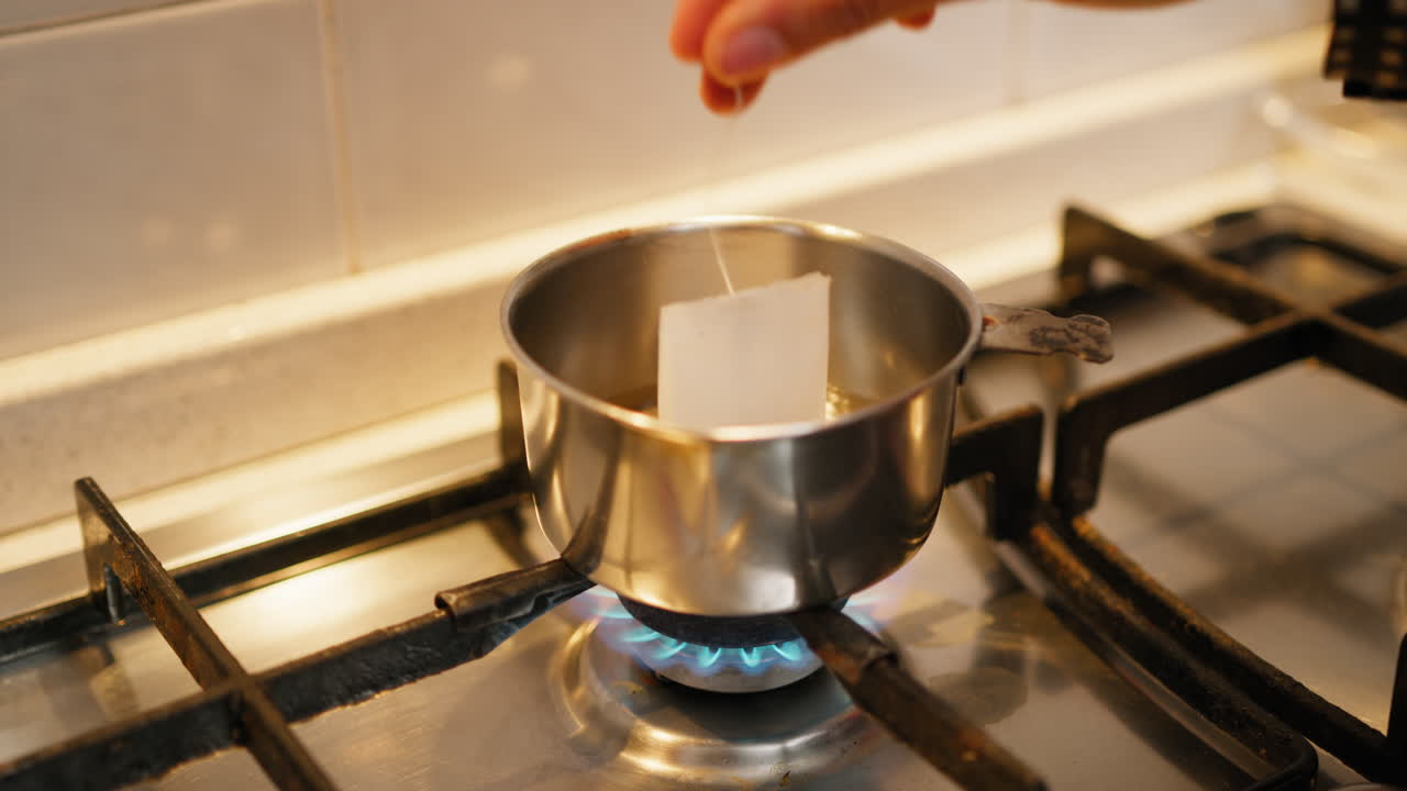 A Woman Hand Dips A Tea Bag Into A Small Pot