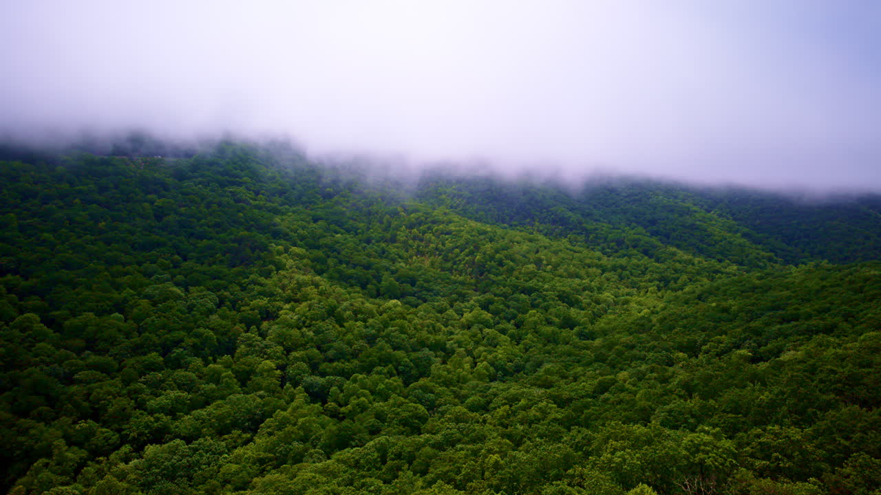 Drone flight showcasing mist flowing over rugged peaks