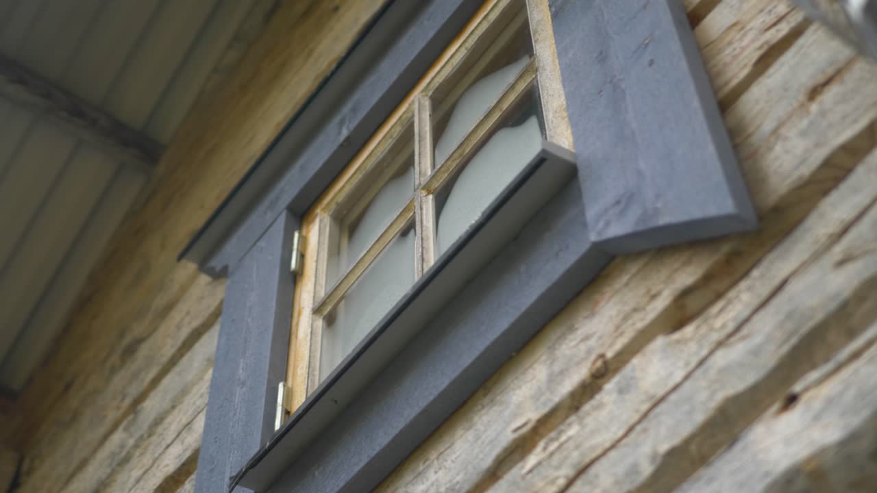 Slow reveal shot of a wind belonging to an old timber cabin in the Scandinavian wilderness