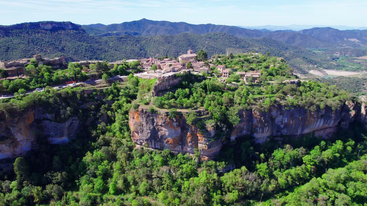 siurana, un pequeño pueblo situado cerca de barcelona, rodeado de grandes árboles y un cielo azul