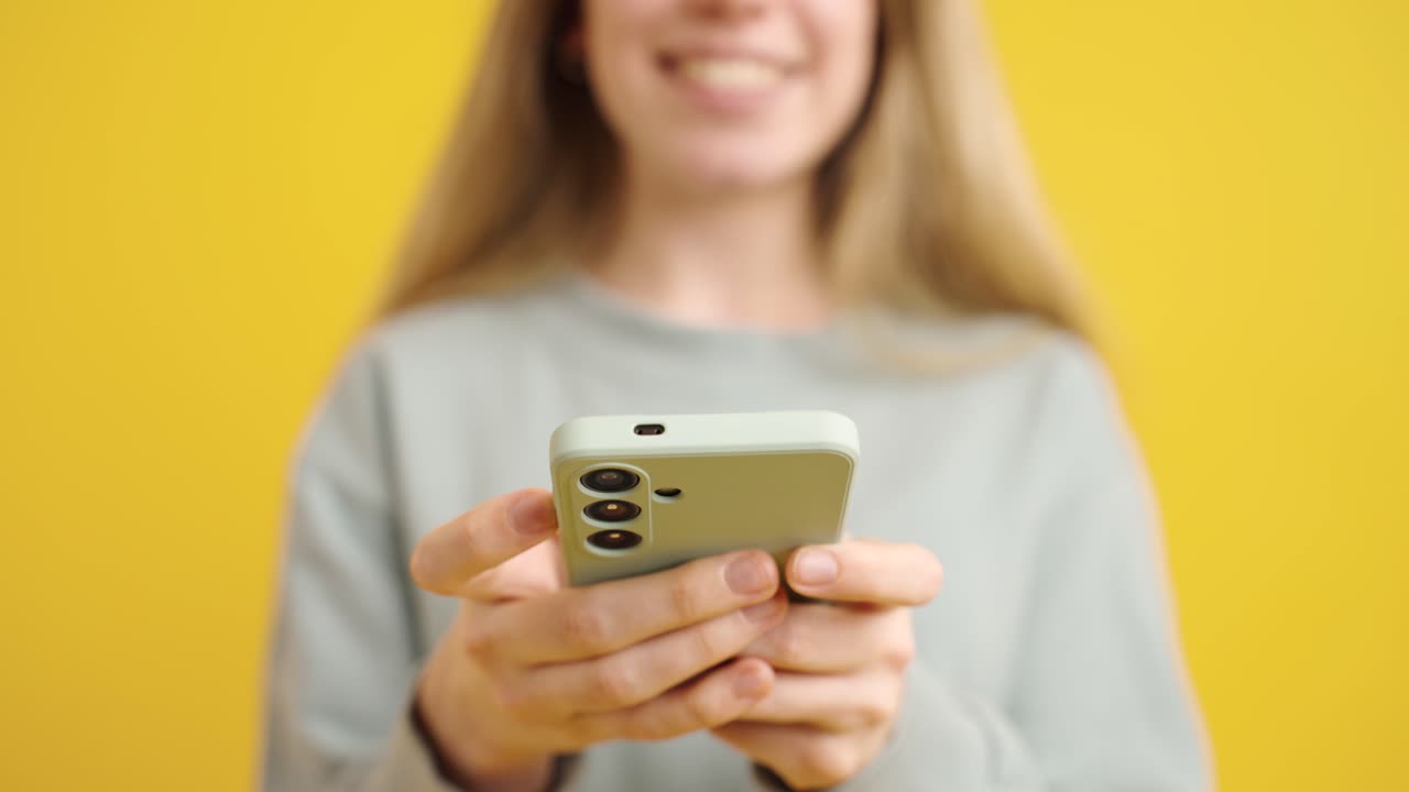 Woman using smartphone on yellow background