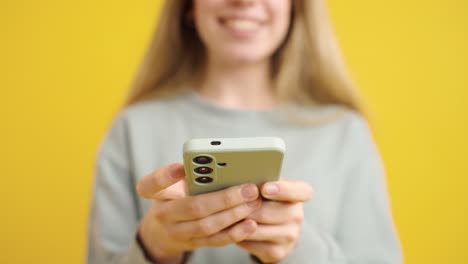 woman using smartphone on yellow background