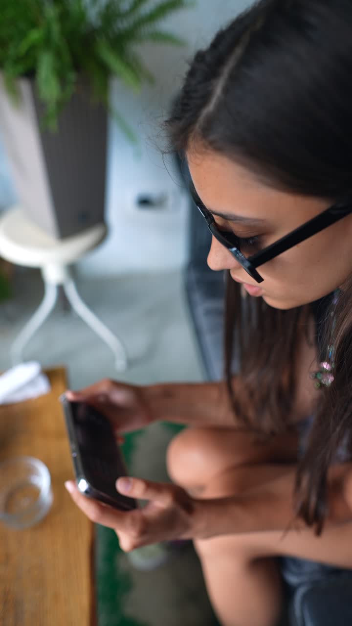 una mujer joven jugando a un juego en su teléfono en un café.