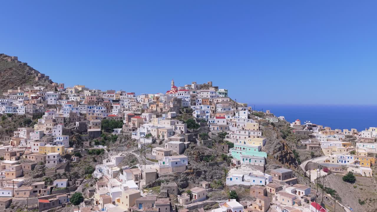 Drone captures Olympos village in Karpathos, gradually revealing the colorful traditional houses and the surrounding mountainous landscape and Aegean scenery