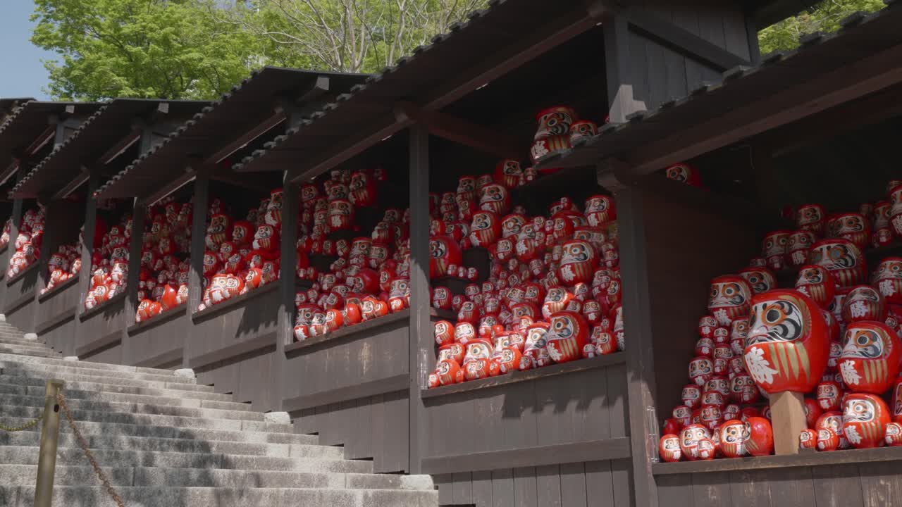 Big red daruma dolls stacked together on a sunny day in Katsuoji Temple, Osaka, Japan