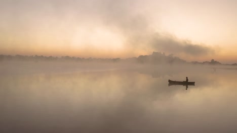 aerial static shot of a man fishing by himself in a big lake in the early morning hours at imire, zimbabwe