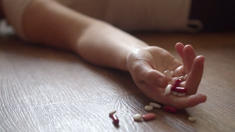 suicide with pills. drug abuse concept, passive hand on floor with spilled pills. close-up