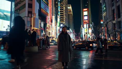 a young woman stands in a vibrant, neon-lit city street at night, surrounded by people and tall buildings