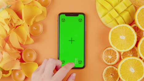 smartphone with green screen display and fresh fruits