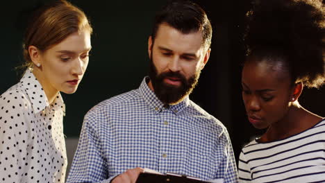 close-up view of caucasian man standing with two coworkers in the office and discussing about a project