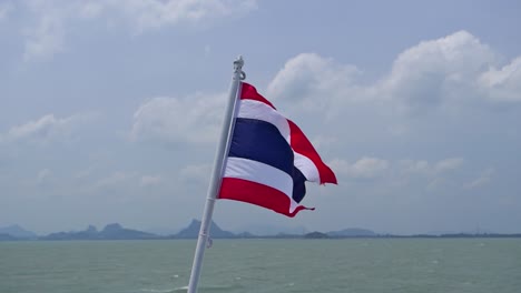 thai flag waving in super slow motion from back of boat on ocean