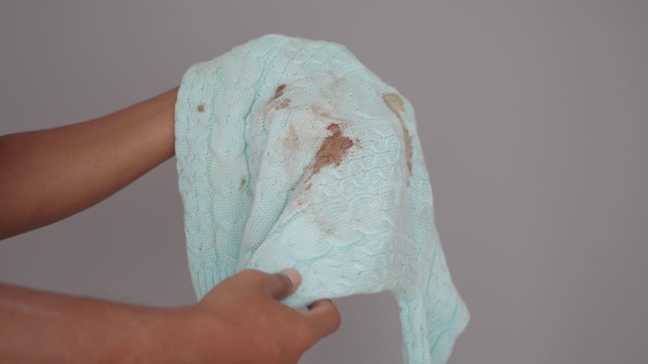 Dirty and stained sweater being held up