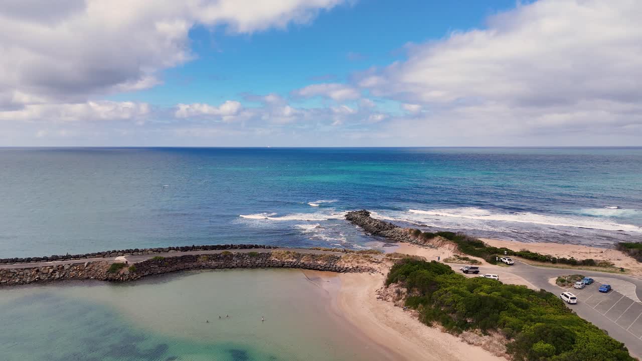 Drone footage captures Lorne's coastline with a jetty, clear skies, and vibrant ocean hues, showcasing the natural beauty of Victoria, Australia
