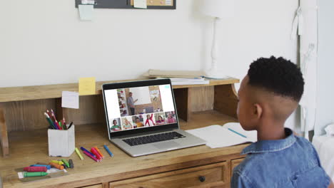 compuesto de un niño que usa una computadora portátil levantando la mano en una lección en línea, un maestro y una clase diversos en la pantalla
