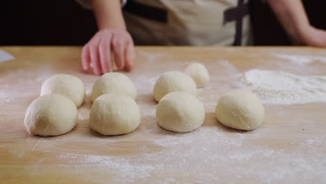 The-baker-rolls-out-the-dough-for-buns-on-the-board.-Working-in-a-bakery.-4k-video