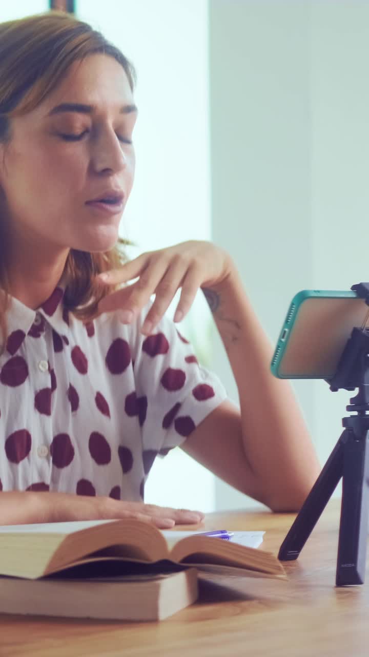Cheerful woman waves during video call while reading book