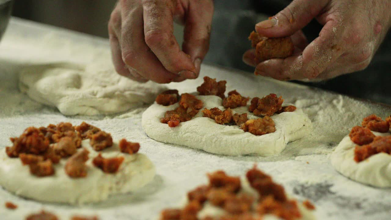 las manos de un panadero añadiendo pudín a la masa