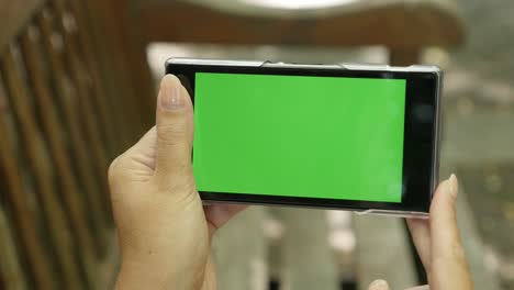 mujer caucásica en el banco sosteniendo la llave de croma teléfono de pantalla verde
