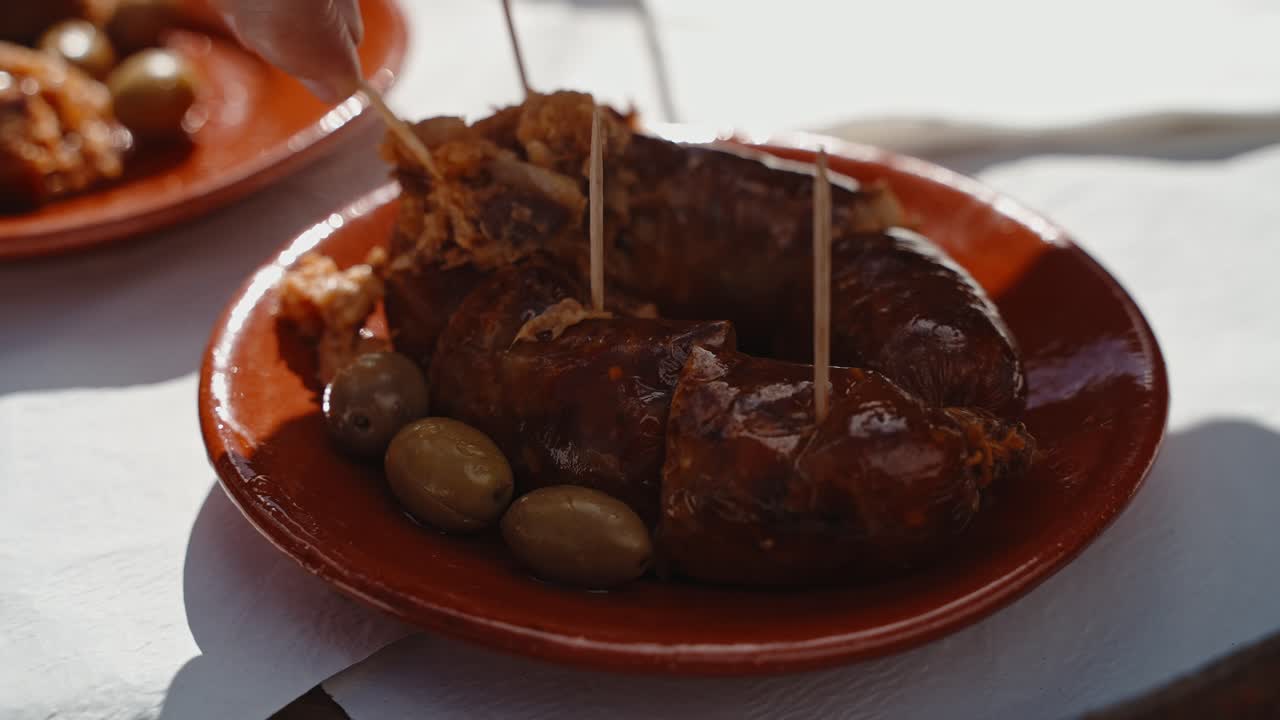 salchicha alheira brillante y aceitunas en un plato de arcilla, comida tradicional portuguesa