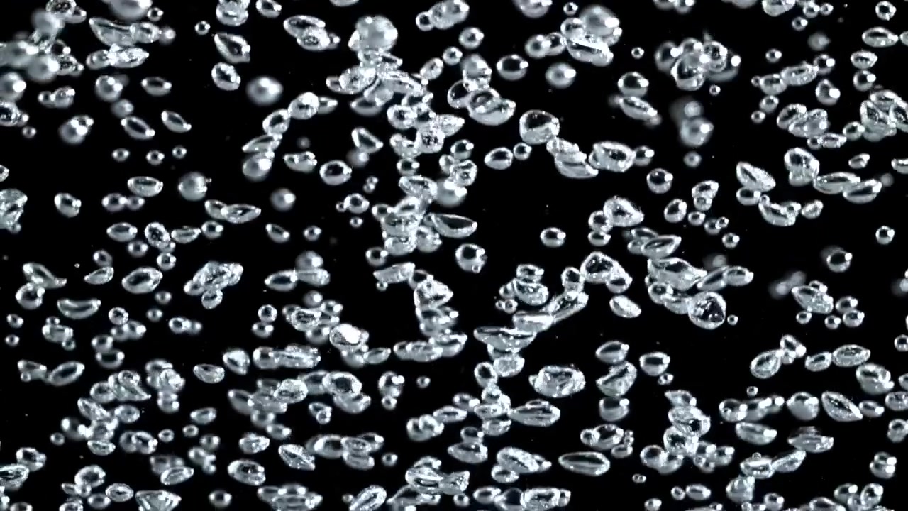Numerose bolle d'aria limpide che fluttuano e risalgono su sfondo nero