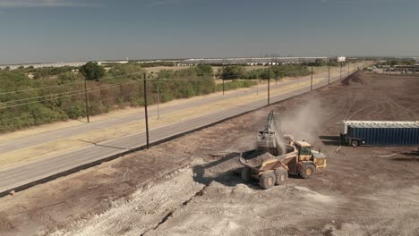 un camión volquete se llena de tierra y rocas por un cargador de grúa