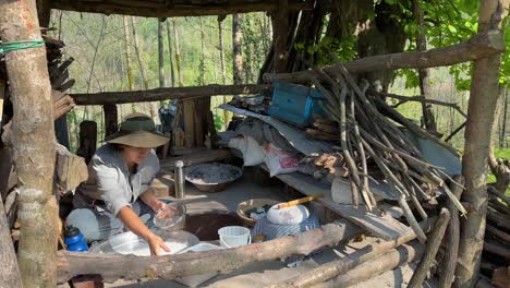 A-beautiful-young-woman-local-people-with-green-hat-sitting-in-traditional-old-wooden-bakery-to-sieve-flour-prepare-dough-fermentation-bake-flat-bread-sweet-saffron-cookies-Fuman-in-rural-life-village