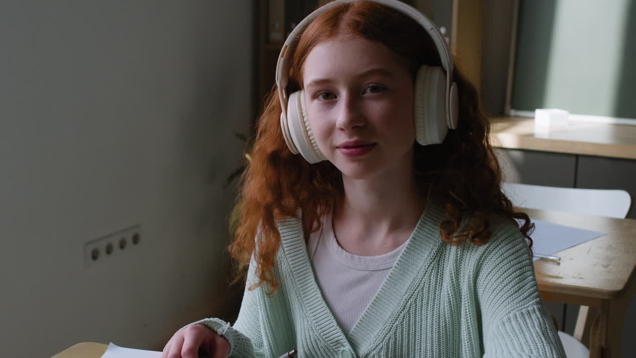 Teenage girl studying with headphones in a classroom