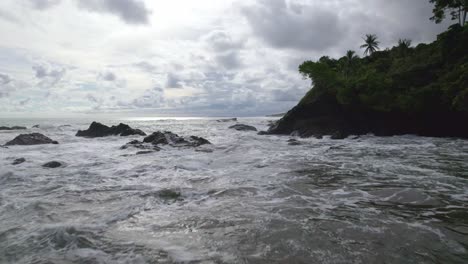 Muñeca-Aérea-Volando-Sobre-Las-Olas-Del-Mar-Golpeando-La-Costa-Rocosa-En-Un-Día-Nublado-En-La-Playa-Dominicalito,-Costa-Rica