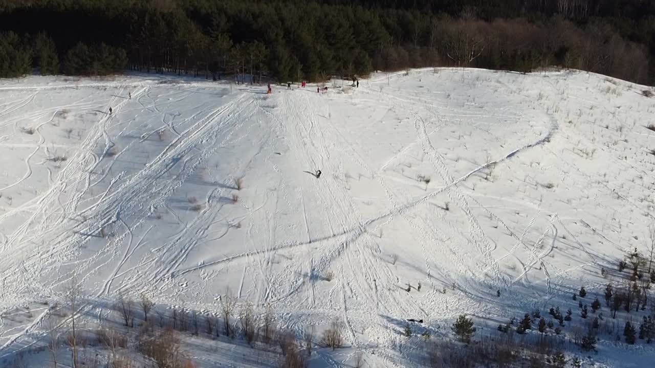 Persone che fanno snowboard e slittano giù per la collina in un parco ricreativo all'aperto.