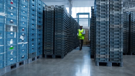 uniformed storehouse employee checking factory product shipment boxes counting