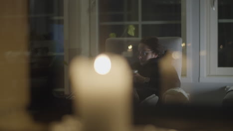 woman relaxing in living room reading book, enjoying drink