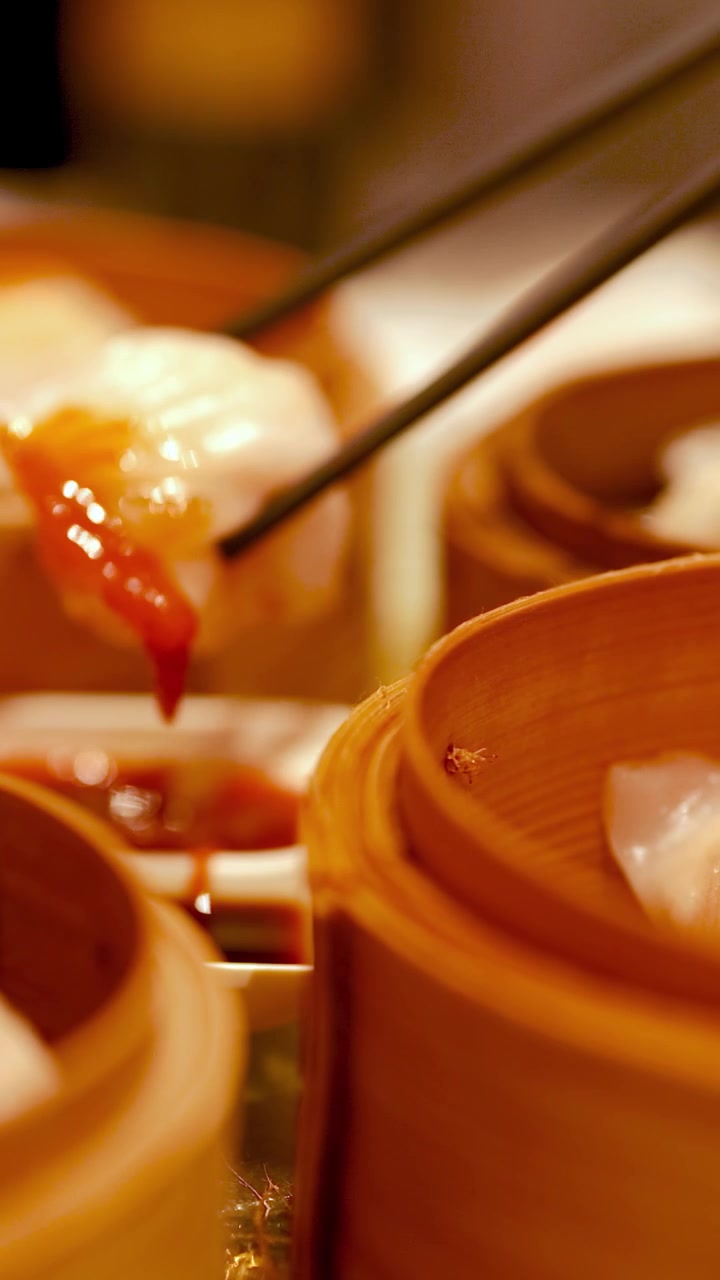 Sumpit dengan hati-hati mengangkat pangsit dari kukusan bambu di restoran dim sum yang bercahaya hangat, menciptakan suasana kuliner yang mengundang.