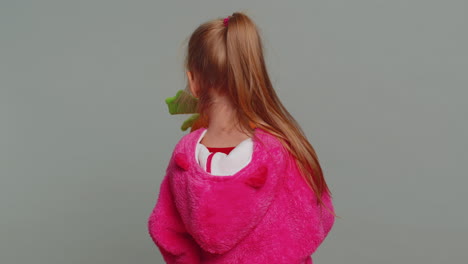 a young girl in a pink fuzzy costume holding a carrot toy