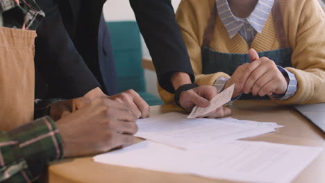 three unrecognizable small business owners doing accounting in their coffee shop 1