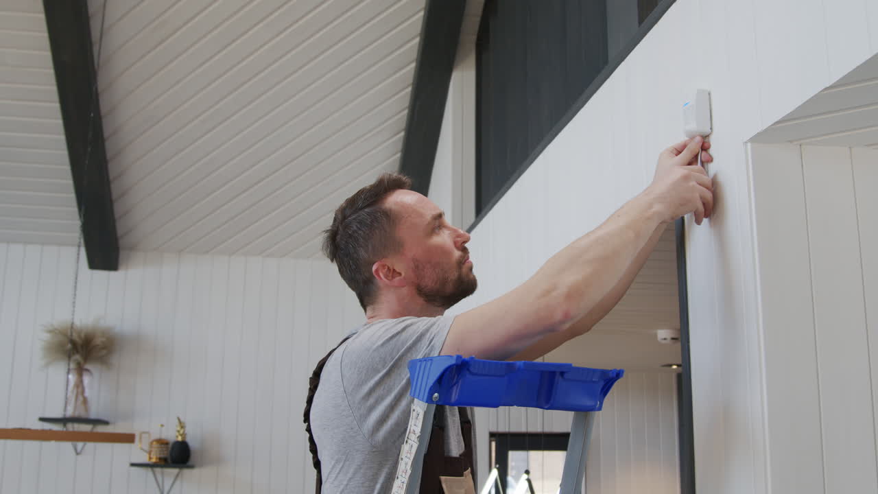 Handyman Getting Up on Ladder and Fixing Sensor